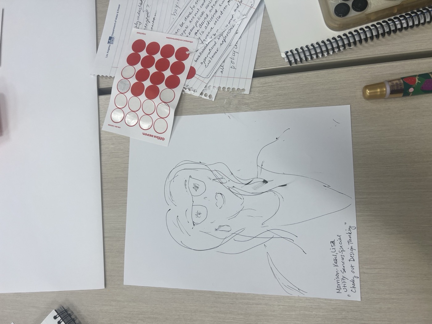 A hand-drawn portrait of a person with glasses on a sheet of paper