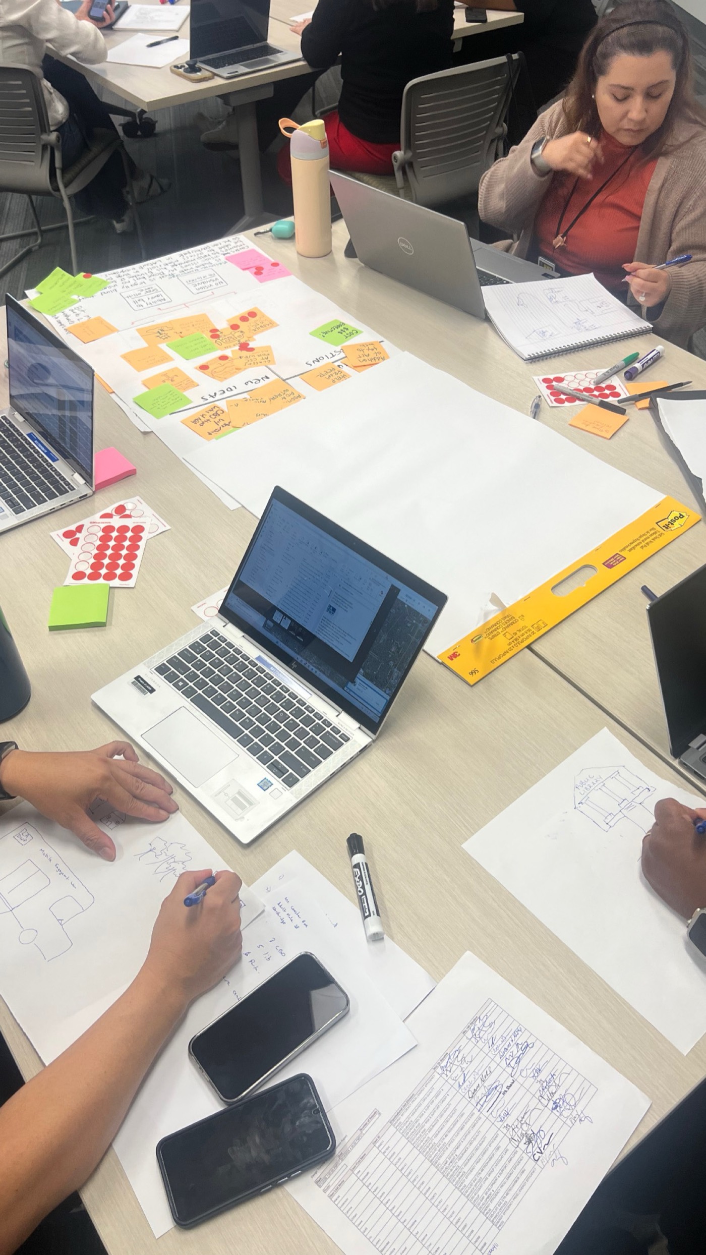 Participants sketching and working on laptops around a table