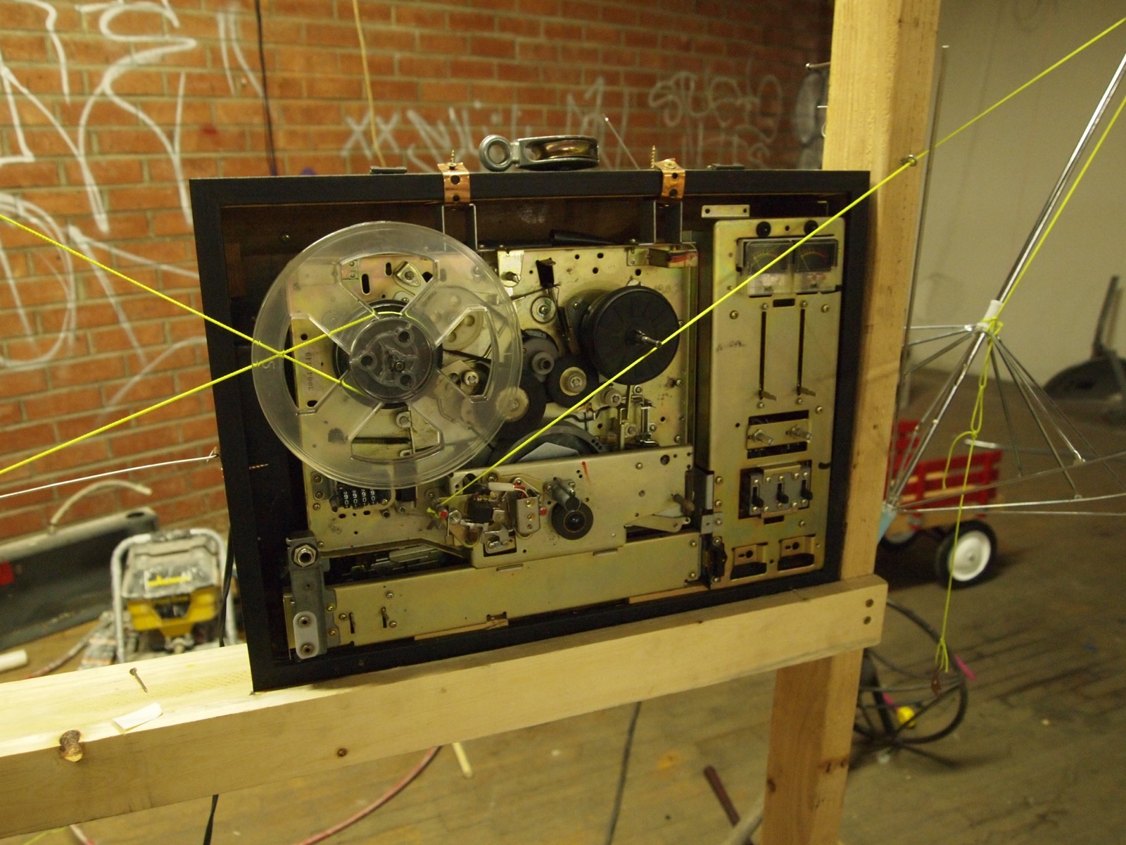 A tape deck mounted on a wooden frame with strings running across it