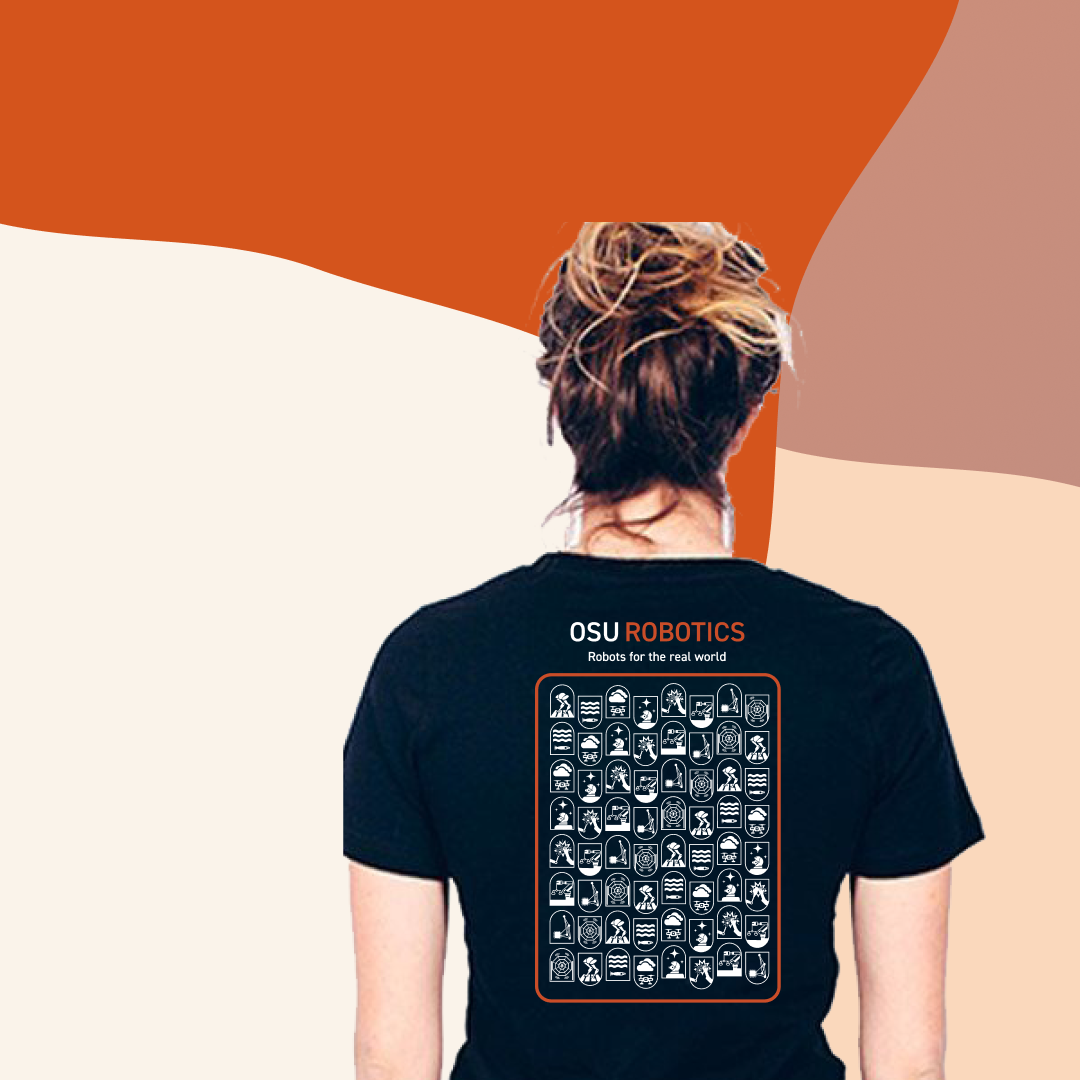 A woman seen from behind wearing the OSU Robotics shirt in front of an orange and cream background